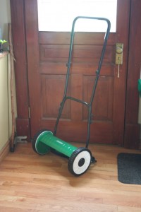 A push reel mower - spinning scythe blades mounted to an axle with a long metal handle for pushing